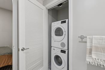 A white washing machine is in a small laundry room. at LiveWell Apartments, Pittsburgh